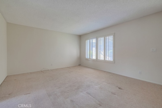 spare room with light colored carpet and a textured ceiling