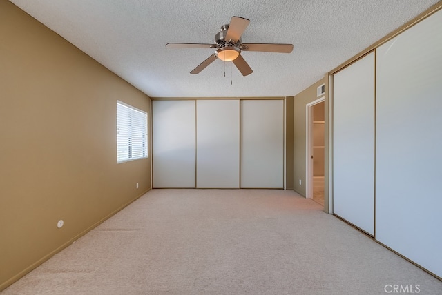 unfurnished bedroom with ceiling fan, light colored carpet, and a textured ceiling