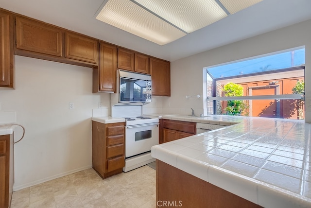 kitchen with sink, tile countertops, white appliances, and kitchen peninsula