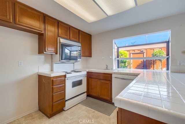 kitchen featuring white appliances, tile counters, and sink