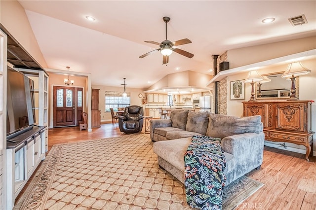 living room with ceiling fan with notable chandelier, light hardwood / wood-style flooring, and lofted ceiling