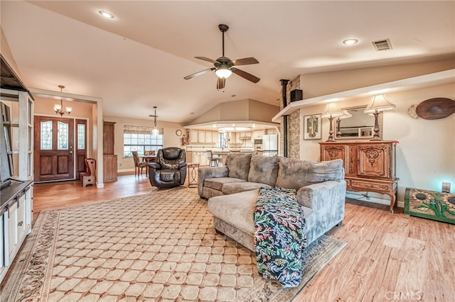 living room with ceiling fan with notable chandelier, light hardwood / wood-style flooring, and lofted ceiling