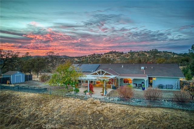 view of front facade featuring solar panels, a storage unit, and a patio area