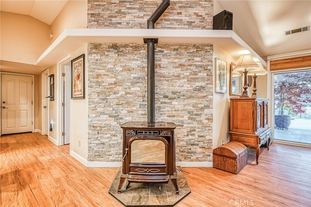 interior space featuring a wood stove, light wood-type flooring, and high vaulted ceiling