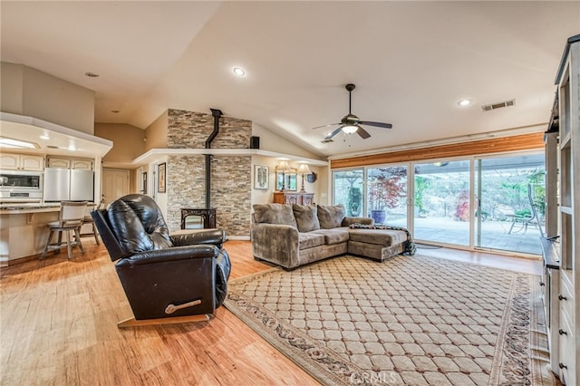 living room featuring wood-type flooring, vaulted ceiling, a wood stove, and ceiling fan