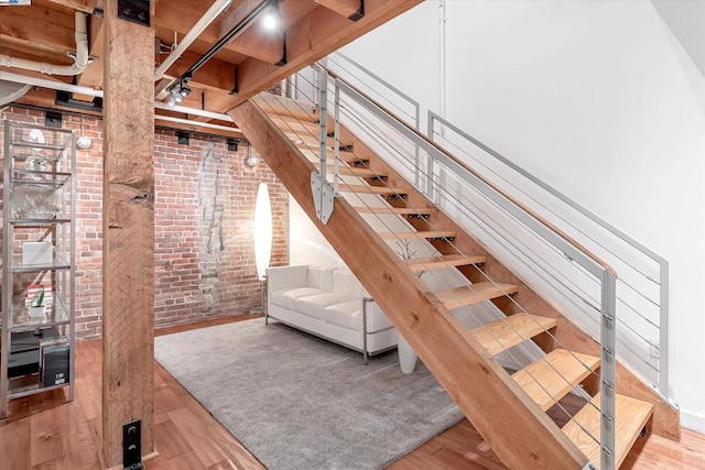 living room featuring hardwood / wood-style flooring, beam ceiling, and brick wall