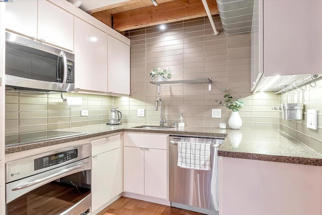 kitchen with sink, white cabinets, stainless steel appliances, and light wood-type flooring