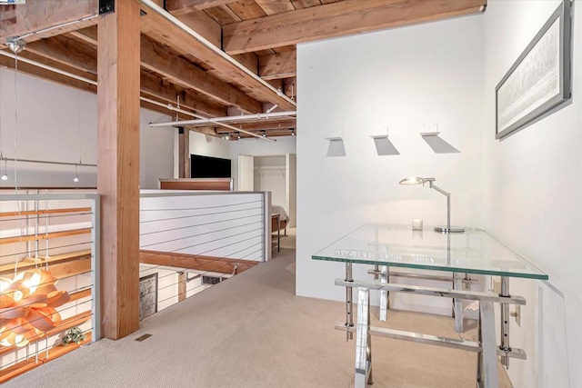 hall featuring beamed ceiling and carpet floors