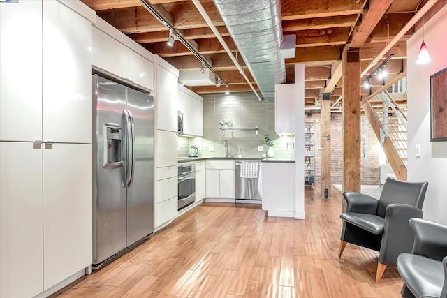 kitchen featuring backsplash, white cabinetry, stainless steel appliances, and light wood-type flooring