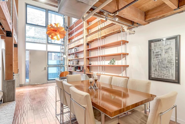 dining area featuring beam ceiling, light wood-type flooring, and wood ceiling