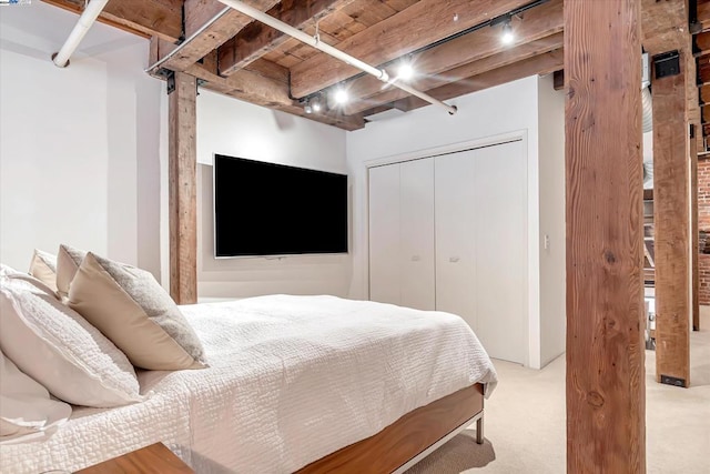 bedroom featuring beam ceiling, light colored carpet, a closet, and wooden ceiling