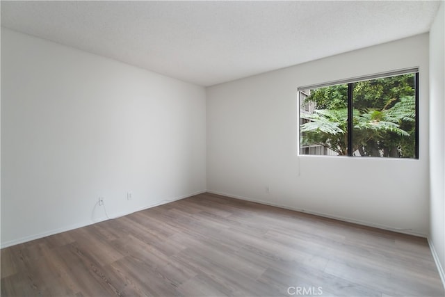 empty room with a textured ceiling and light wood-type flooring