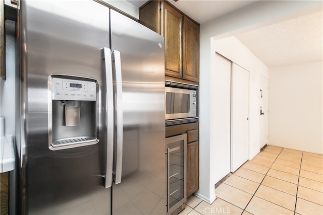 kitchen featuring light tile patterned floors, stainless steel appliances, and beverage cooler