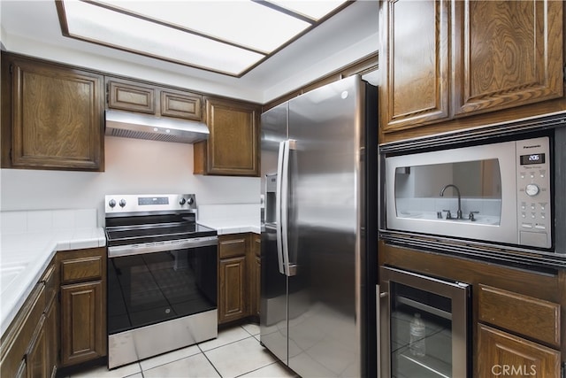 kitchen featuring dark brown cabinets, light tile patterned floors, and stainless steel appliances