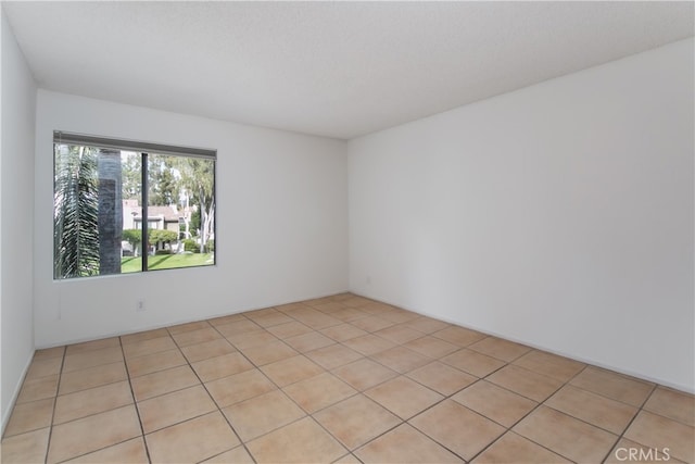 empty room with light tile patterned floors and a textured ceiling