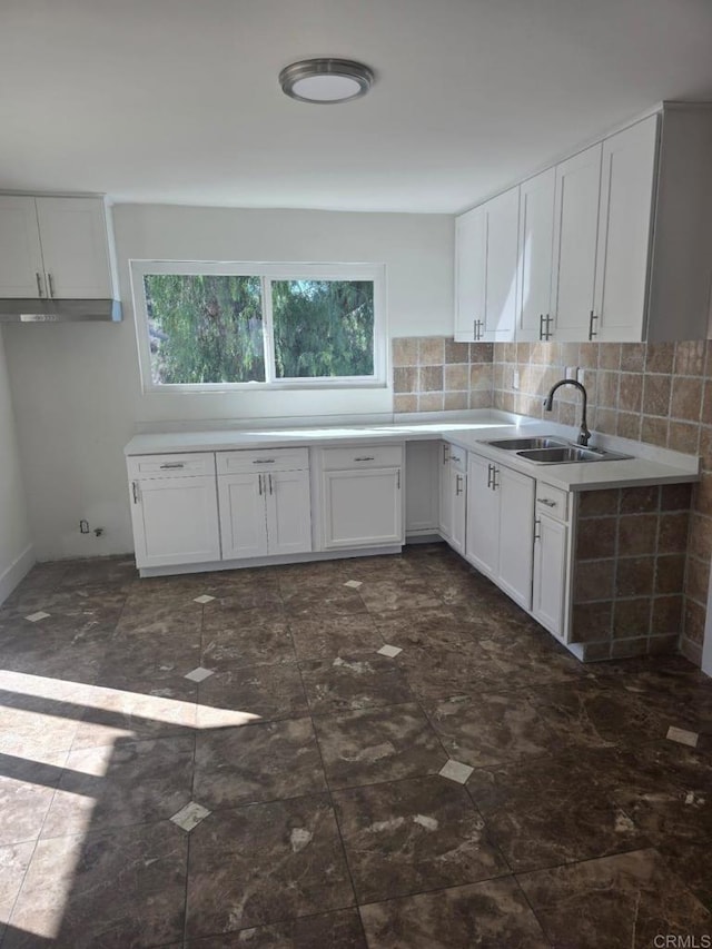 kitchen with tasteful backsplash, sink, and white cabinetry