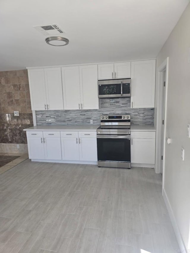 kitchen with stainless steel appliances, decorative backsplash, and white cabinets