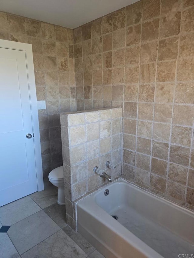 bathroom featuring tile patterned floors, tile walls, toilet, and a bathing tub