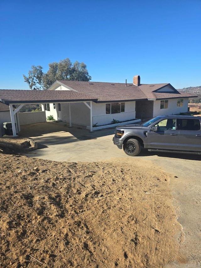 ranch-style house with a carport and a chimney