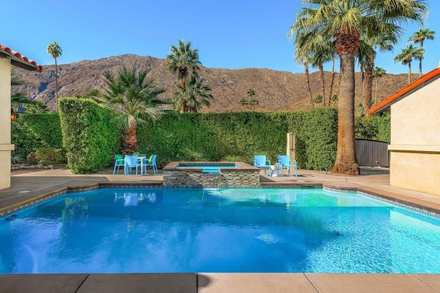 view of swimming pool with a mountain view, a patio area, and an in ground hot tub