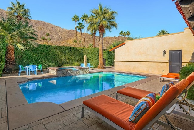 view of pool featuring an in ground hot tub, a mountain view, and a patio