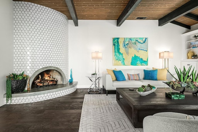 living room with lofted ceiling with beams, a tiled fireplace, wood-type flooring, and wooden ceiling