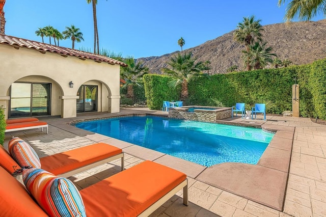 view of pool featuring a mountain view, a patio, and an in ground hot tub