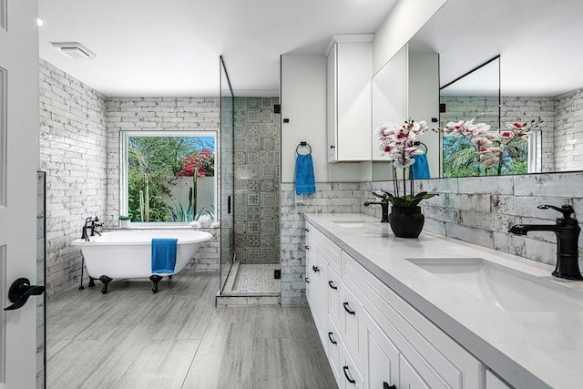 bathroom featuring plus walk in shower, vanity, and tile walls