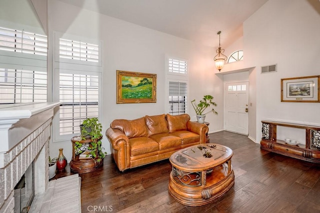 living area with visible vents, baseboards, a fireplace, wood finished floors, and high vaulted ceiling