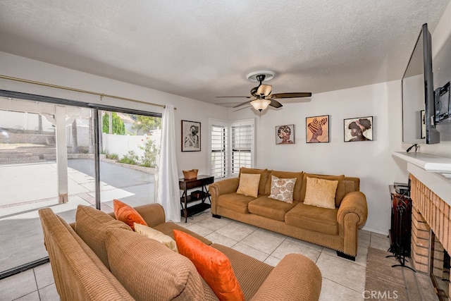 tiled living room featuring a textured ceiling, a brick fireplace, and ceiling fan