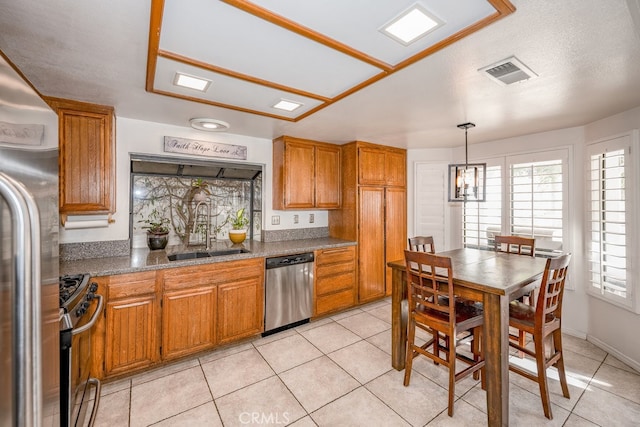 kitchen featuring pendant lighting, stainless steel appliances, light tile patterned floors, and sink