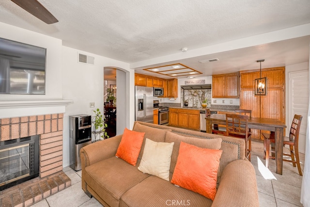 living room with a fireplace, light tile patterned floors, and a textured ceiling