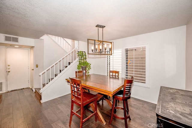 dining area with visible vents, dark wood finished floors, stairway, an inviting chandelier, and a textured ceiling