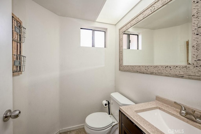 bathroom with vanity, toilet, and baseboards