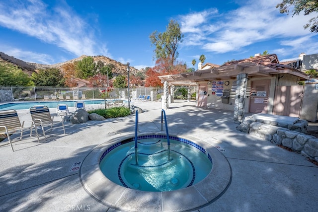 view of swimming pool featuring a mountain view, a community hot tub, a pergola, and a patio