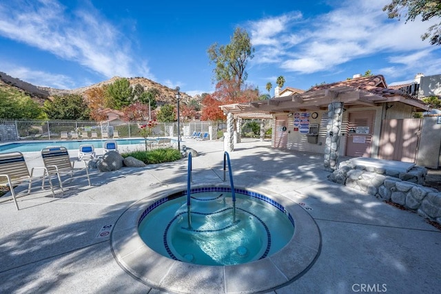 community pool featuring a patio, a hot tub, a pergola, and fence