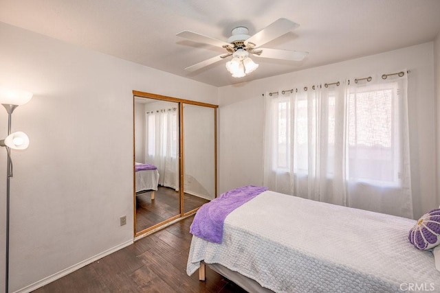 bedroom featuring dark wood-style floors, baseboards, a closet, and a ceiling fan