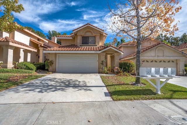 mediterranean / spanish home with a tile roof, a garage, driveway, and stucco siding