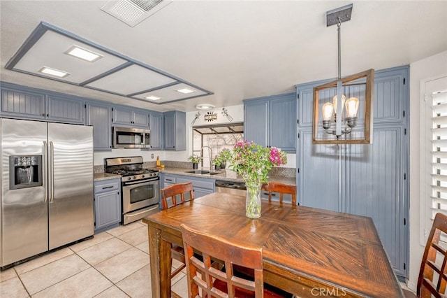 kitchen featuring visible vents, a sink, decorative light fixtures, appliances with stainless steel finishes, and light tile patterned flooring