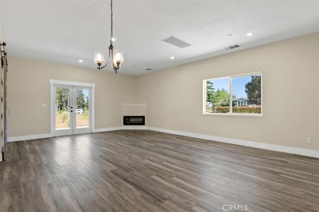 unfurnished living room featuring french doors, a chandelier, and dark hardwood / wood-style floors