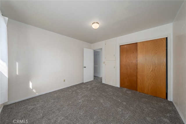 unfurnished bedroom featuring a closet and dark colored carpet