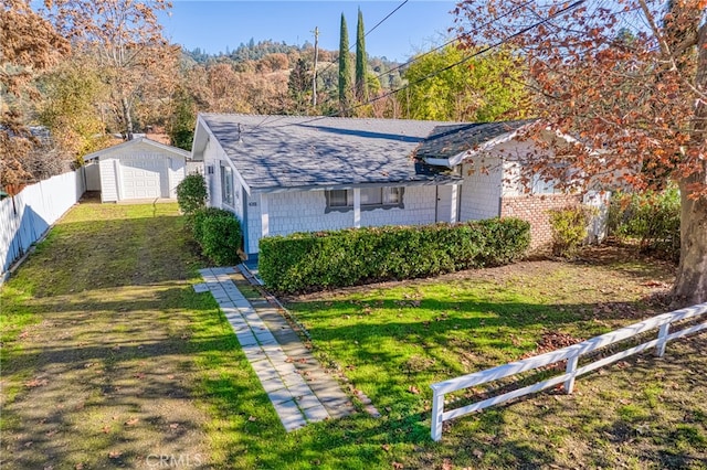 view of front of property featuring a garage, a front lawn, and an outdoor structure