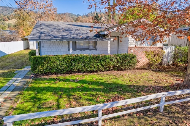 single story home featuring a mountain view and a front lawn