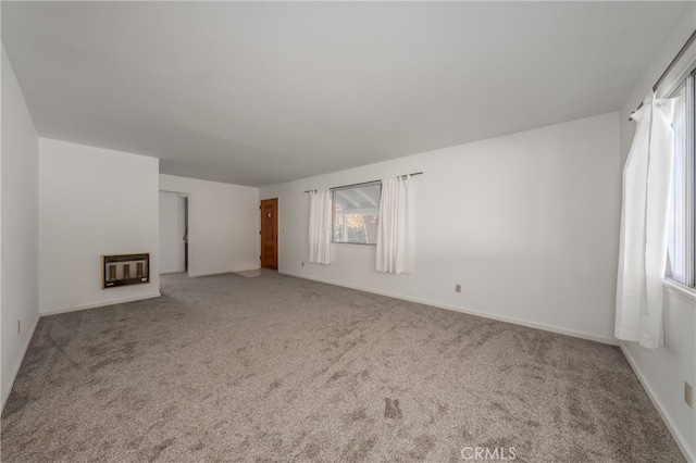 unfurnished living room with carpet floors, heating unit, and a wealth of natural light