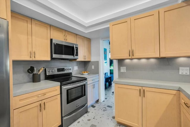 kitchen with appliances with stainless steel finishes, light brown cabinets, and tasteful backsplash