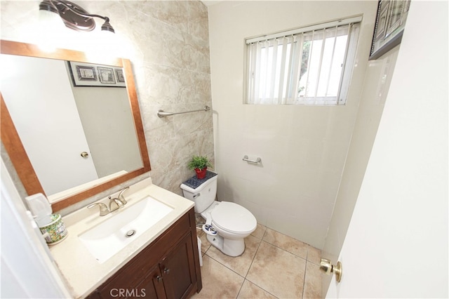 bathroom featuring toilet, vanity, tile patterned floors, and tile walls