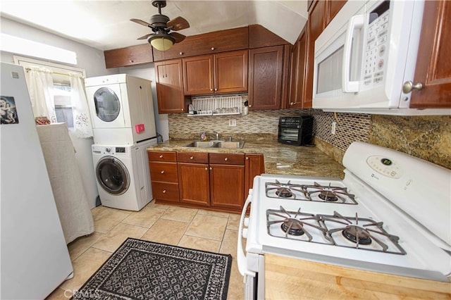 kitchen featuring ceiling fan, sink, stacked washing maching and dryer, tasteful backsplash, and white appliances