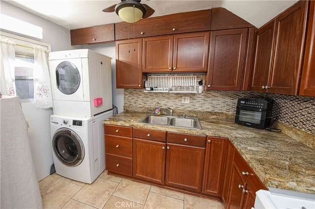 clothes washing area featuring stacked washer / dryer, ceiling fan, sink, and light tile patterned flooring