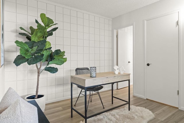 office area featuring a textured ceiling, light hardwood / wood-style flooring, and tile walls