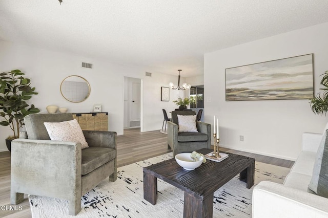 living room with a notable chandelier, a textured ceiling, and light hardwood / wood-style flooring